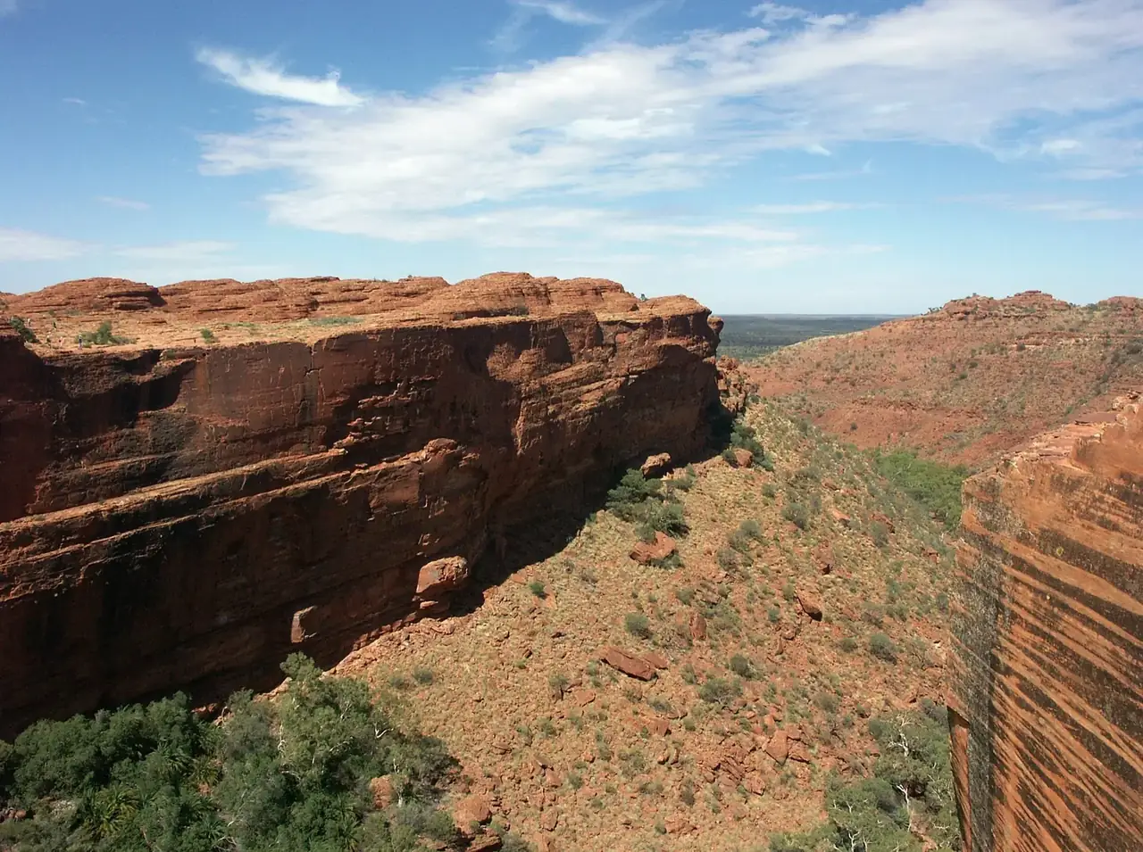 The red sandstone walls of Kings Canyon rising above the scrub of Watarrka National Park