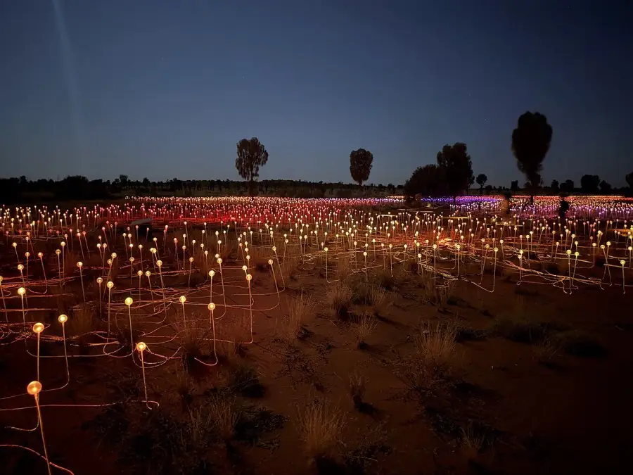 Thousands of lit glass spheres covering the desert floor at dusk