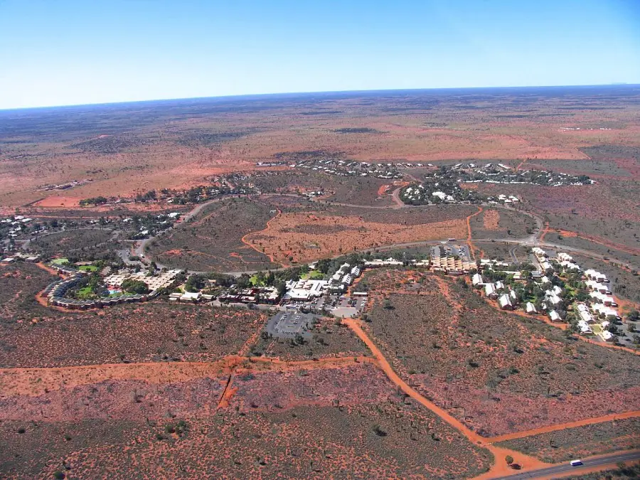 Yulara resort seen from a helicopter, low buildings scattered across red sand
