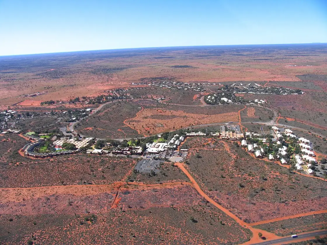 A scenic helicopter on the pad at Yulara with the desert behind it